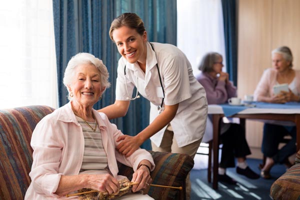 Portrait of smiling female doctor with senior woman at retirement home